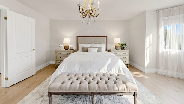 Ein Schlafzimmer mit einem großen Bett, zwei Nachttischen, einer Chandelier und einem großen Fenster mit durchsichtigen Vorhängen.