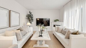 Ein modernes Wohnzimmer mit zwei weißen Sofas, einem Couchtisch und einem Fernseher.