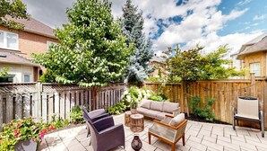 Eine Terrassenfläche mit Gartenmöbeln, einem Holzzaun und verschiedenen Pflanzen.