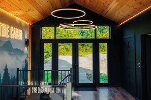 Ein Holzhaus-Interieur mit Holzbalkendecke, einer Treppe und Blick ins Grüne.