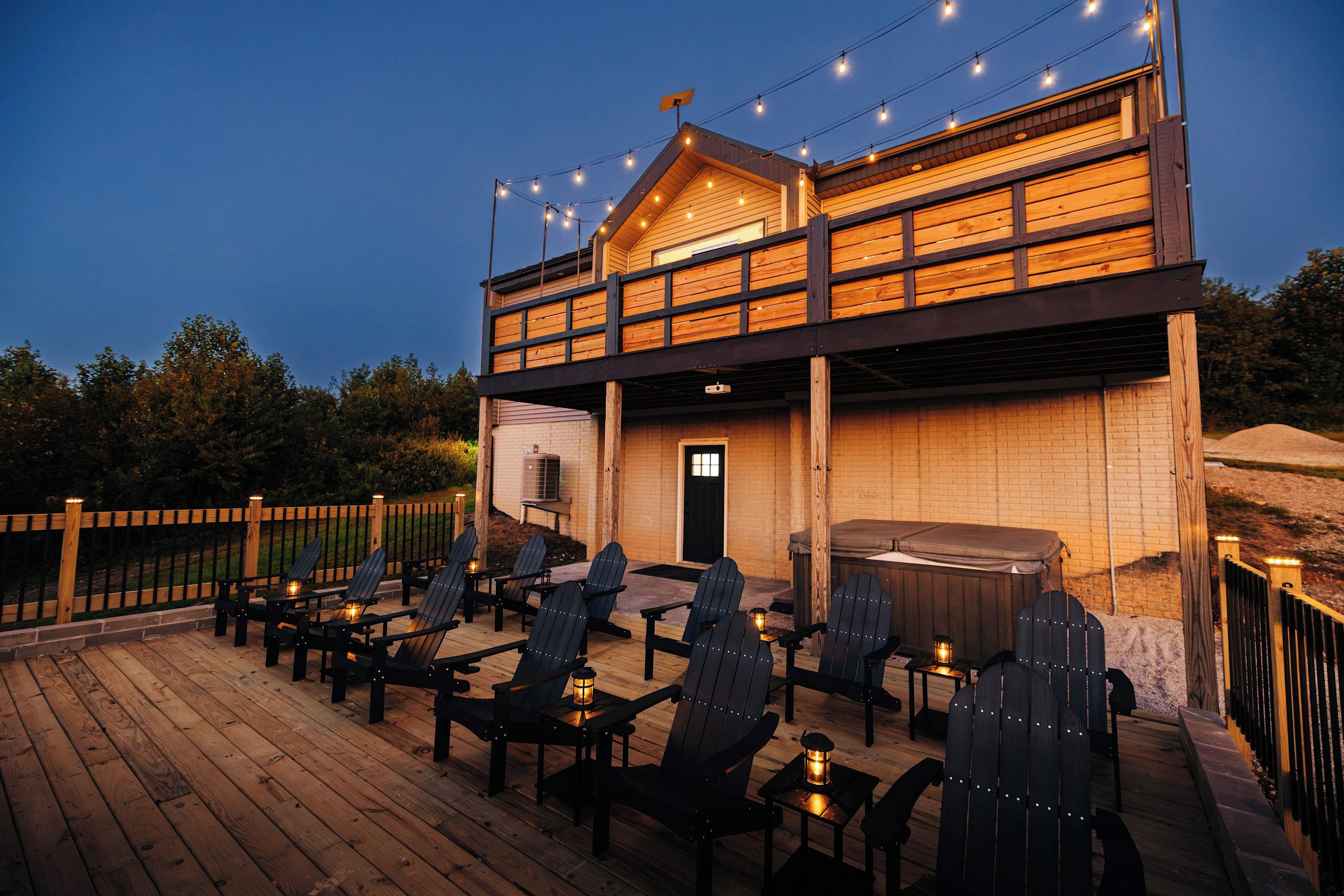 A wooden deck with outdoor seating and string lights.