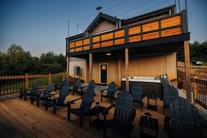 A wooden deck with Adirondack chairs and a hot tub.