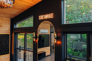 Ein modernes Interieur mit einem 'STAY AWAY'-Schild, großen Fenstern und Blick auf Grünflächen.