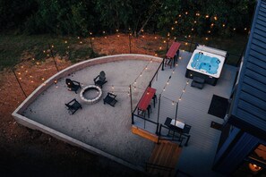 A rooftop patio with a hot tub, seating area, and string lights. - The Overlook A Luxury Cabin With Hot Tub And Views (New Plymouth)