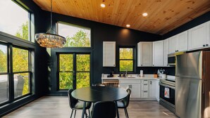 Una cocina moderna con amplios ventanales, una mesa de comedor y electrodomésticos de acero inoxidable.