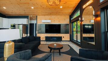 Een moderne woonkamer met een grote televisie, comfortabele zitplaatsen en een kroonluchter.