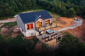 Une maison à deux étages avec un balcon, un jacuzzi et une terrasse avec des chaises.