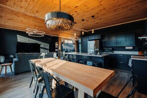 Una cocina moderna con armarios oscuros, una isla central y una lámpara colgante.