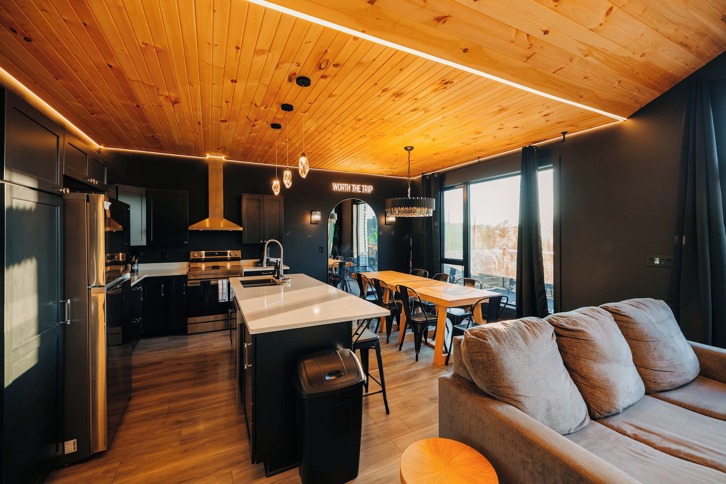 A modern kitchen with a central island, stainless steel appliances, and a dining area with a large window.