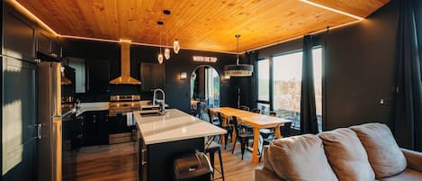 A modern kitchen with a central island, stainless steel appliances, and a dining area with a large window.