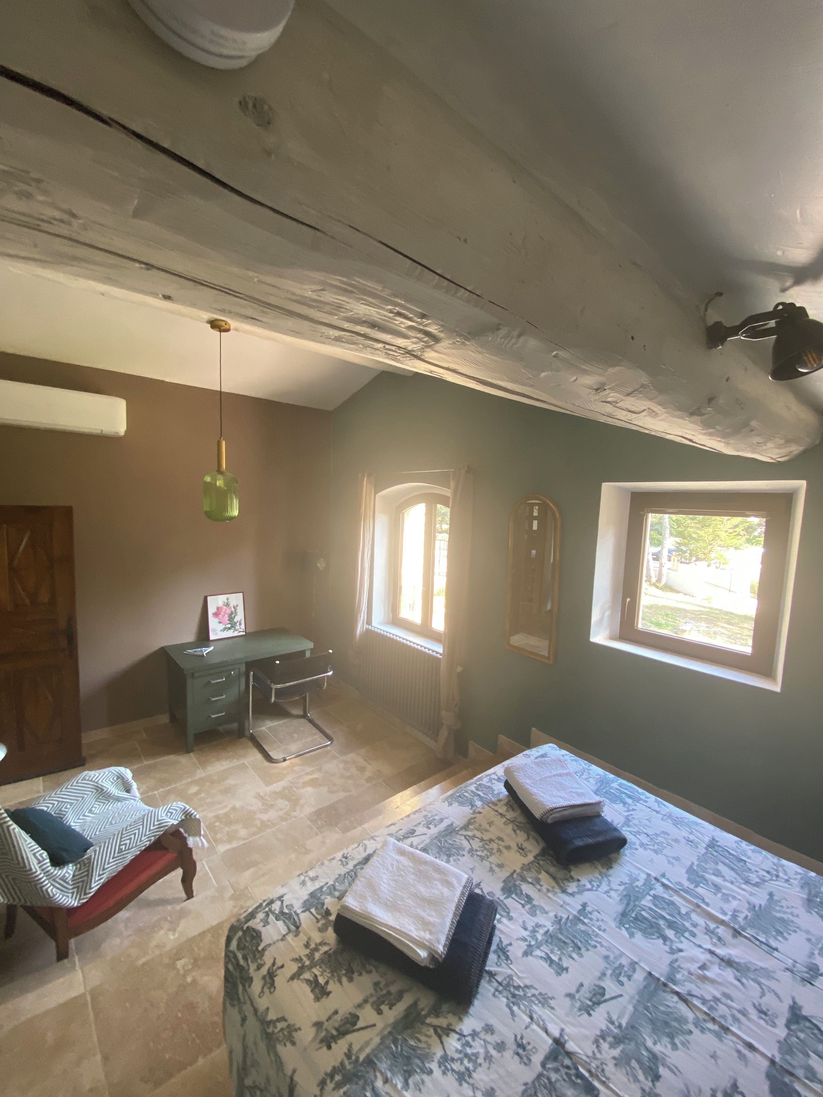 A room with a bed, a desk, a chair, a radiator, and a window.