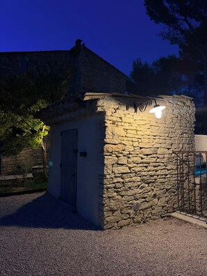A stone building with a door and a small window, surrounded by gravel and trees. - 🌿 La Bastide de la Colline, an authentic Provençal house with a private pool. (Cavaillon)