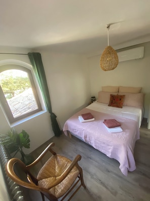 A bedroom with a bed, a chair, a hanging light fixture, a window with curtains, and a potted plant. - 🌿 La Bastide de la Colline, an authentic Provençal house with a private pool. (Cavaillon)