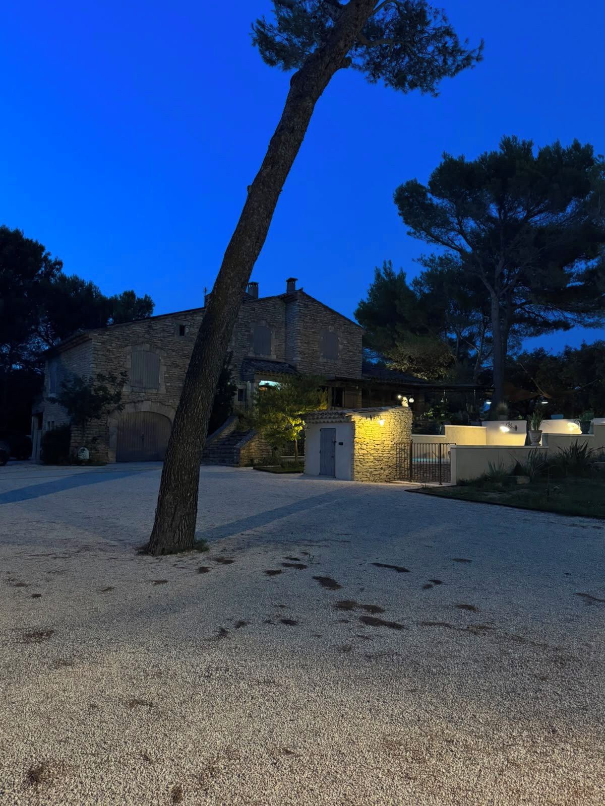 Una casa de piedra con camino de grava y una pequeña verja.