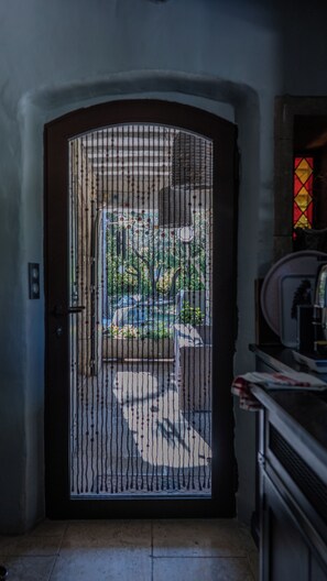 A door with a decorative metal grille, leading to an outdoor area with a bench and greenery. - 🌿 La Bastide de la Colline, an authentic Provençal house with a private pool. (Cavaillon)