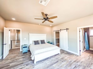 A bedroom with a bed, a ceiling fan, a walk-in closet, and a staircase. - NEW Longtown Lakefront Retreat | Boat Slip | Game Room | Sleeps 10 (Eufaula)