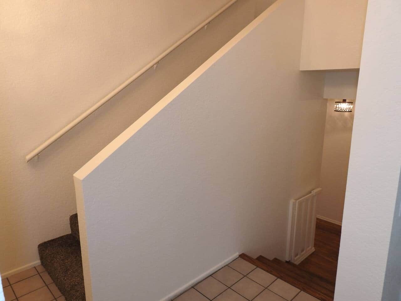 Un escalier avec des murs blancs et un plancher en bois.