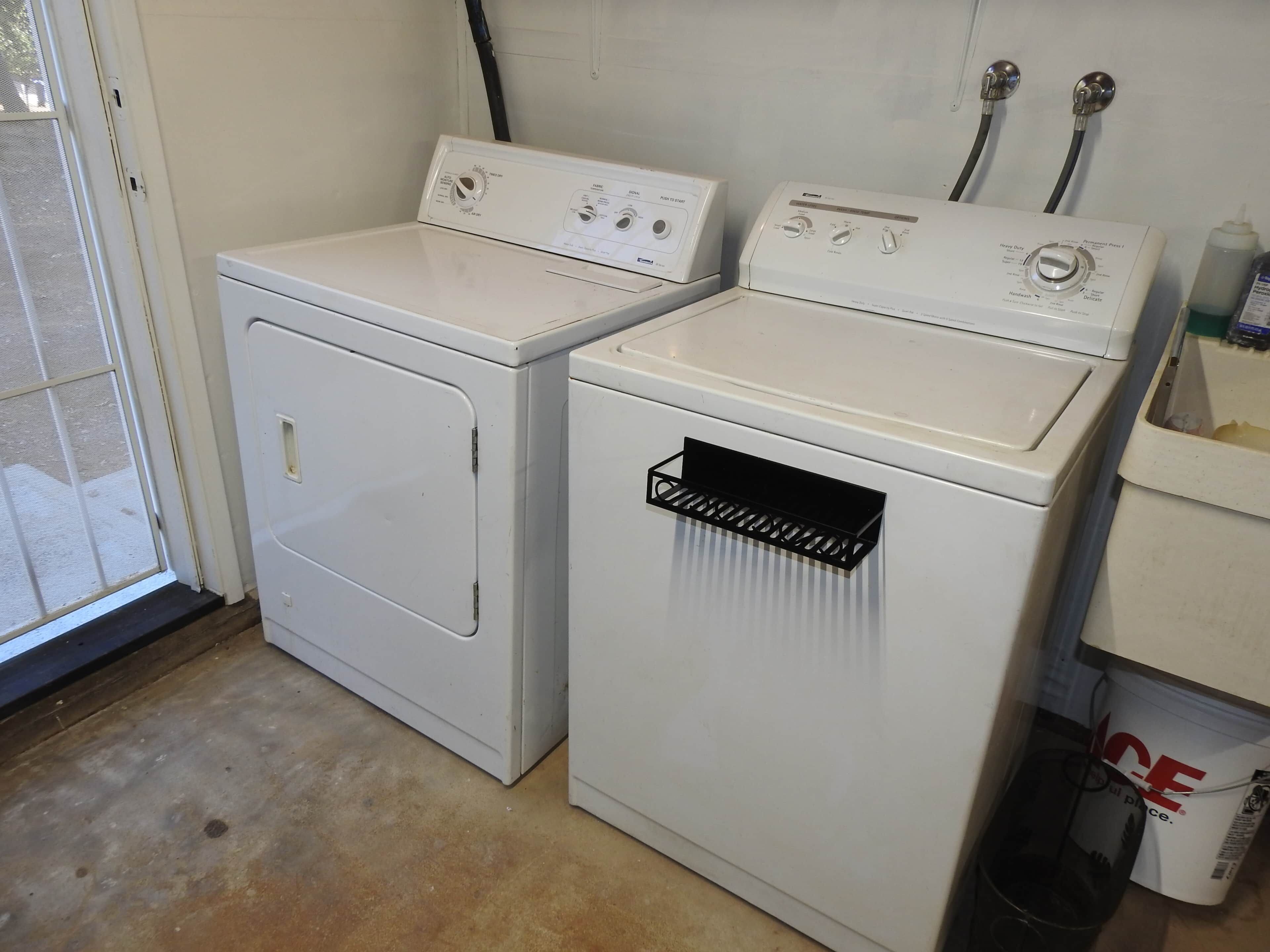 A laundry area with two white washing machines, one with a front-loading door and the other with a top-loading door.