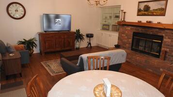 A living room with a television, fireplace, dining table, and seating area.