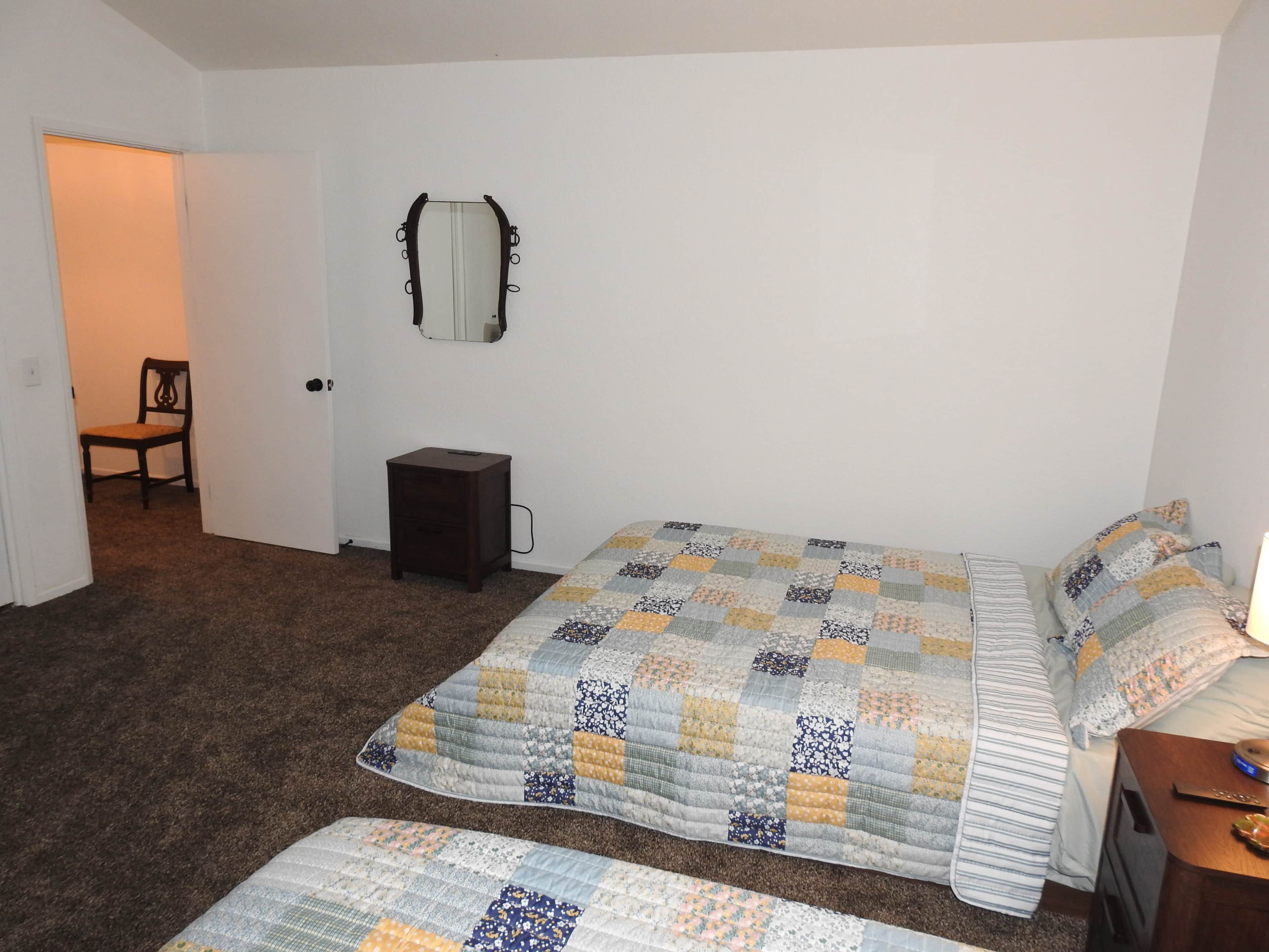 Une chambre à coucher avec un lit, une chaise, une commode et un miroir au mur.