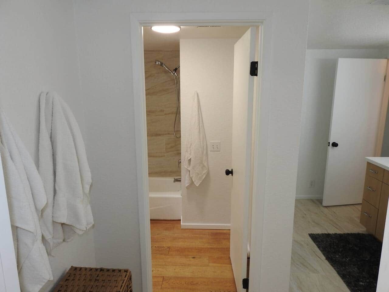 Un baño con ducha, toallero y piso de madera.