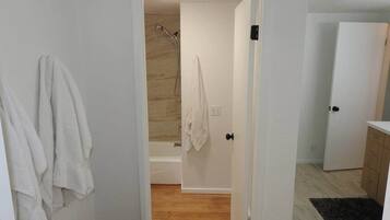 Un baño con ducha, toallero y piso de madera.
