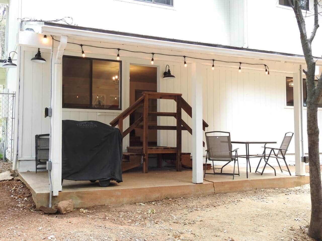 A covered outdoor area with a grill, a staircase, and a table with chairs.