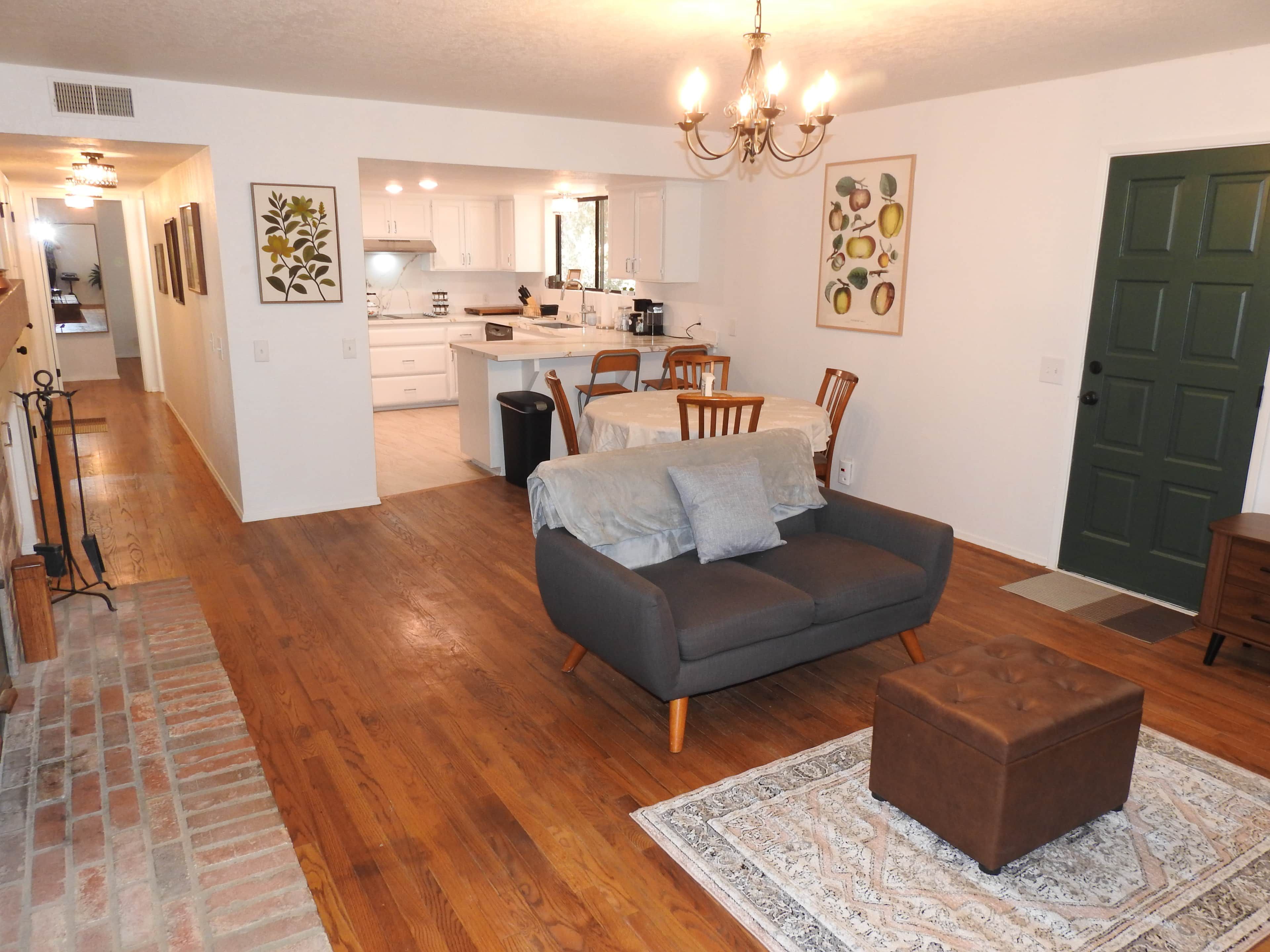 A modern living room with a sofa, ottoman, and a dining area with chairs.
