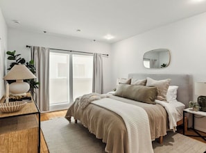 A bedroom with a bed, bedside table, lamp, and a view of the outdoors. - 2-bedroom apartment in Brentwood. The den/office is ideal for working from home (Los Angeles)