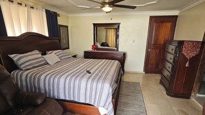 Ein Schlafzimmer mit Bett, Sofa, Kommode, Spiegel und Deckenventilator.