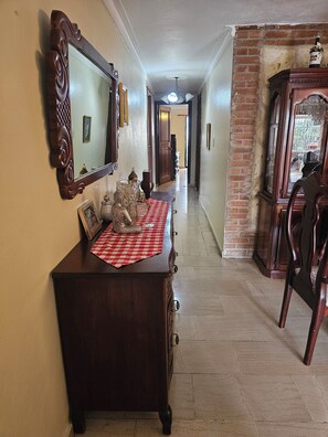 Un couloir avec une commode en bois, un miroir et une nappe à carreaux.