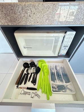 A drawer with kitchen utensils, including knives, spoons, and spatulas, neatly organized. - Melhores Flats - Divino, pertinho do mar (João Pessoa)
