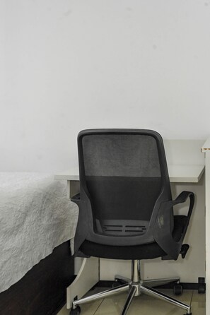 A black office chair with a mesh backrest and a five-point base, positioned in front of a white desk with a white cloth on it. - Costa Linda Modern Apto·Walk to the beach·Pool/AC (Punta Arenas)