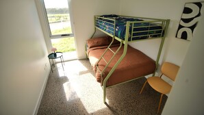 Huoneessa on kerrossänky, ikkuna, pieni pöytä ja tuoli.