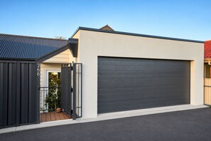 A modern two-story building with a garage door, a metal gate, and a number '266' on the gate.