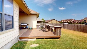A backyard with a wooden deck, a barbecue grill, and outdoor furniture. - Wrangler Hideaway - 3.6 miles to Kyle Field (College Station)