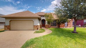 A residential house with a garage, a front yard with a tree, and a driveway. - Wrangler Hideaway - 3.6 miles to Kyle Field (College Station)