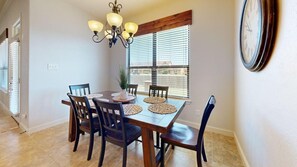 A dining area with a wooden table, six chairs, and a chandelier. - Wrangler Hideaway - 3.6 miles to Kyle Field (College Station)