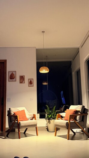 A living room with two sofas, a coffee table, and a hanging light fixture. - Country house with heated pool in the heart of Cantareira, 30 minutes from São Paulo. (Caieiras)