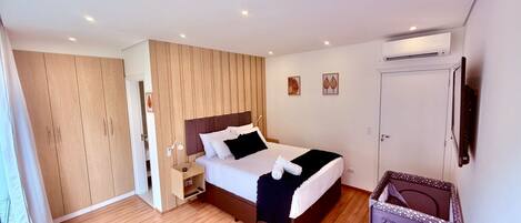 A modern bedroom with a bed, bedside table, wardrobe, and an air conditioning unit.