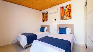 Una habitación de hotel con dos camas, techo de madera y dos cuadros en la pared.