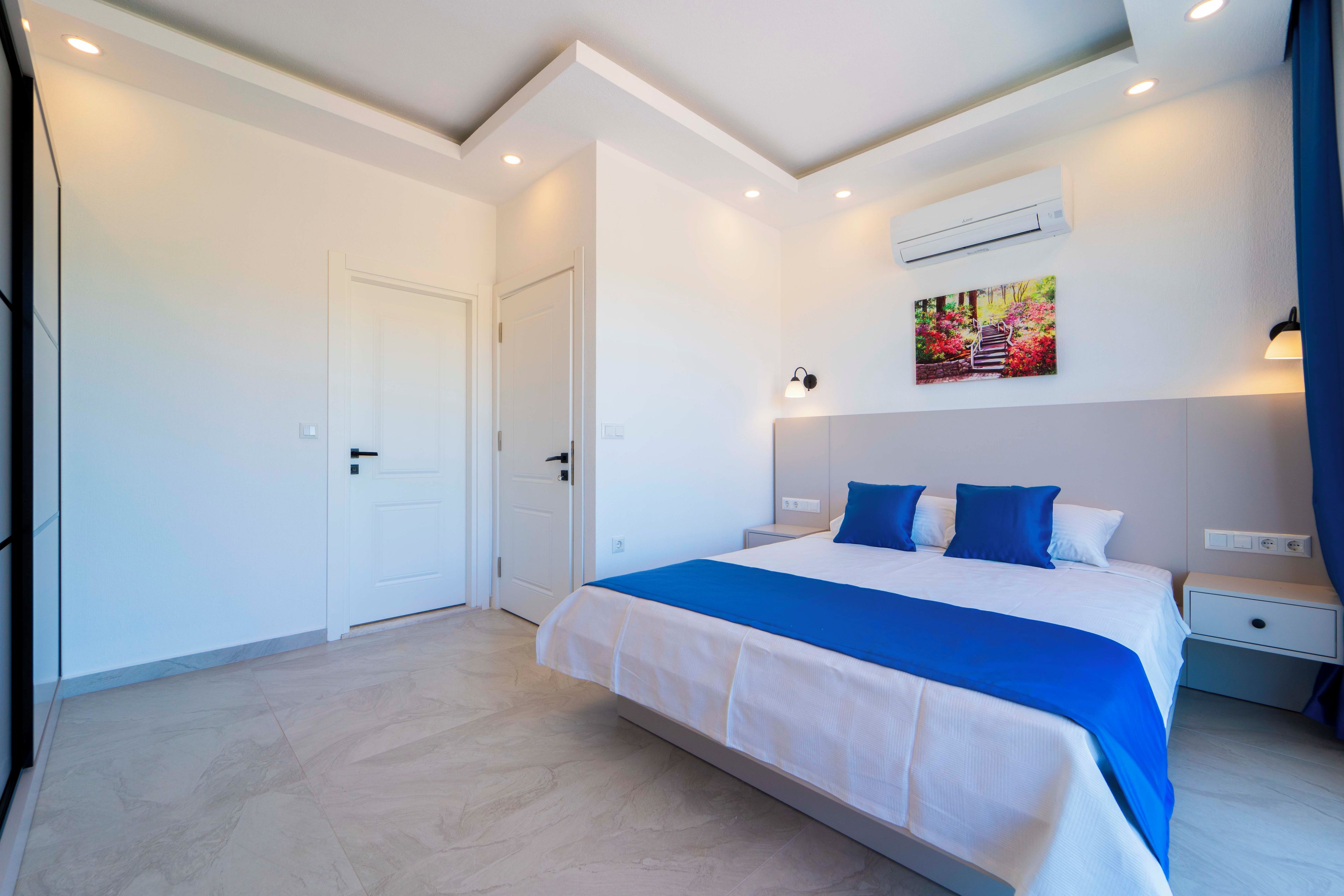 Une chambre d’hôtel avec un lit, des tables de chevet, un appareil de climatisation et un tableau au mur.