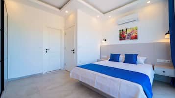 Una habitación de hotel con cama, mesitas de noche, equipo de aire acondicionado y un cuadro en la pared.