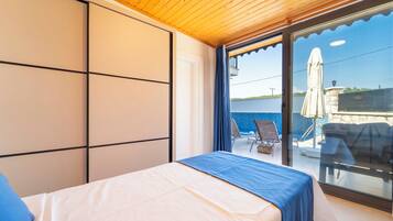 A bedroom with a bed, a view of the sea, and a balcony with outdoor furniture.