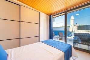 A bedroom with a bed, a view of the sea, and a balcony with outdoor furniture.