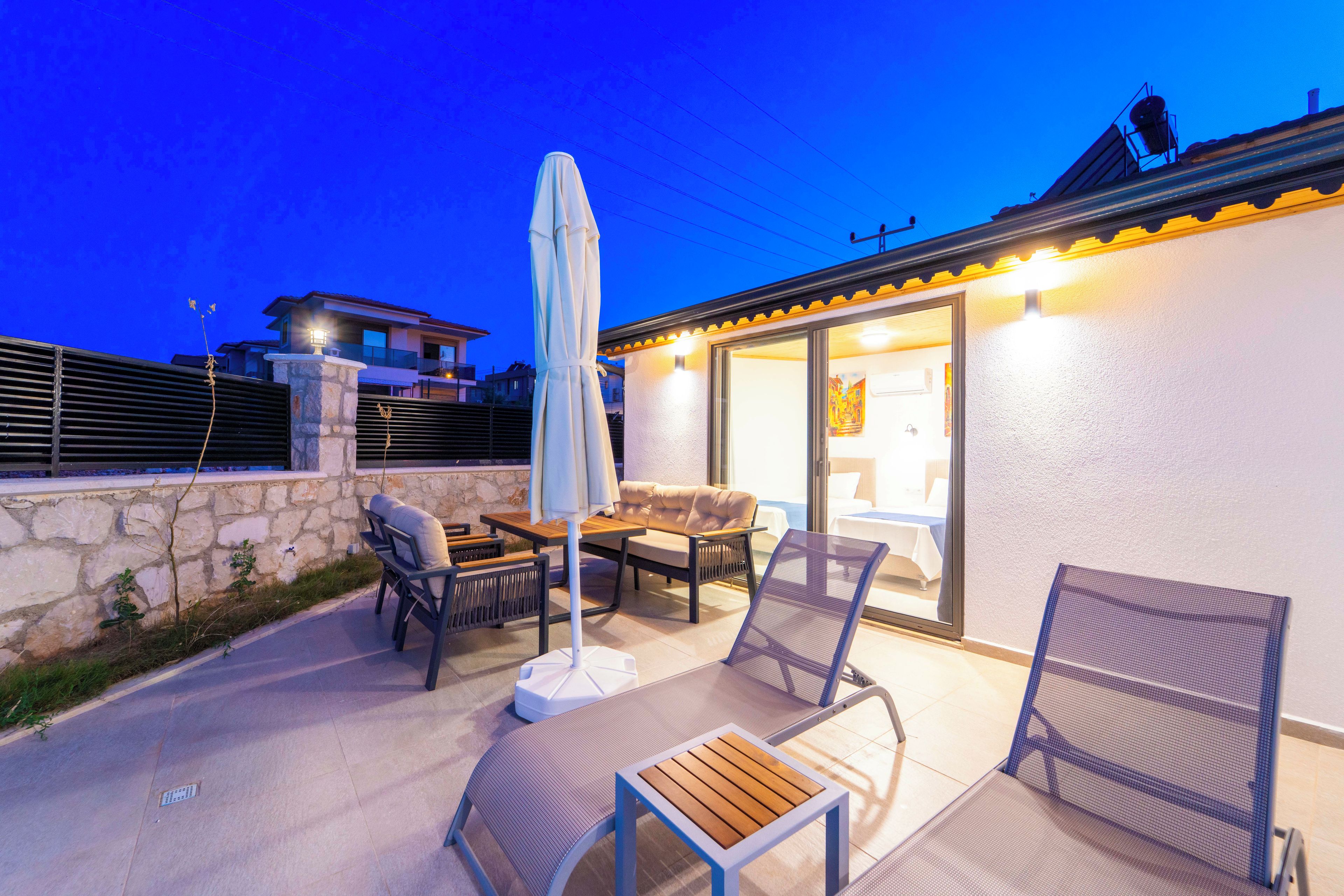 Un patio amoblado con muebles de exterior, una mesa y un gran paraguas.