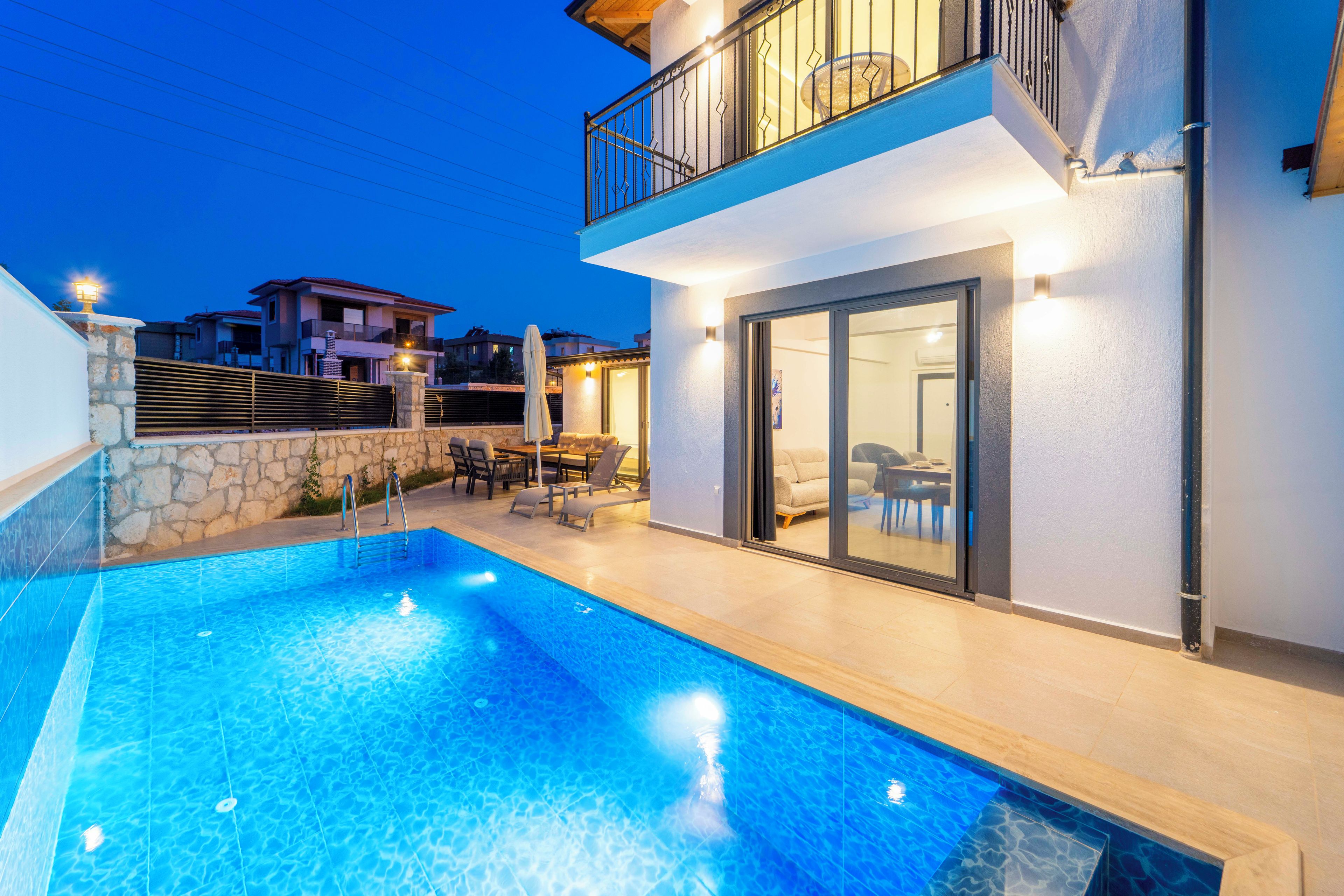 Ein modernes, zweistöckiges Haus mit Swimmingpool, Gartenmöbeln und einem Balkon.