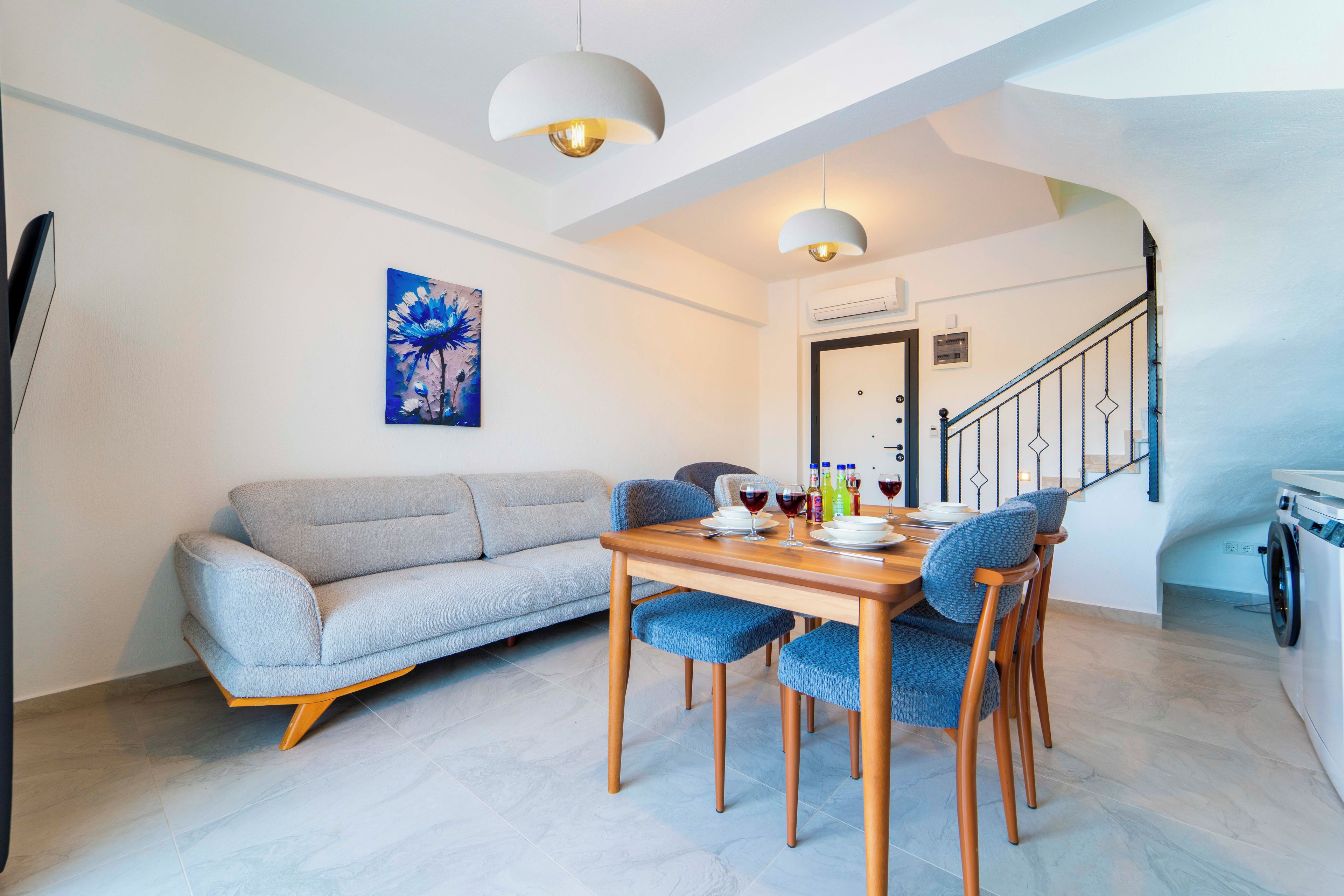 A modern living room with a sofa, dining table, chairs, and a painting on the wall.