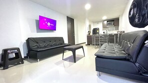 A modern living room with a black sofa, a small table, and a flat-screen TV mounted on the wall. - Conquistadores Apartamentos (Medellín)