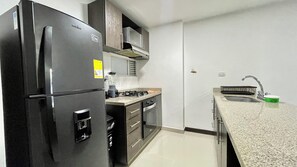Une cuisine compacte équipée d’un réfrigérateur, d’une cuisinière, d’un four à micro-ondes et d’un évier.